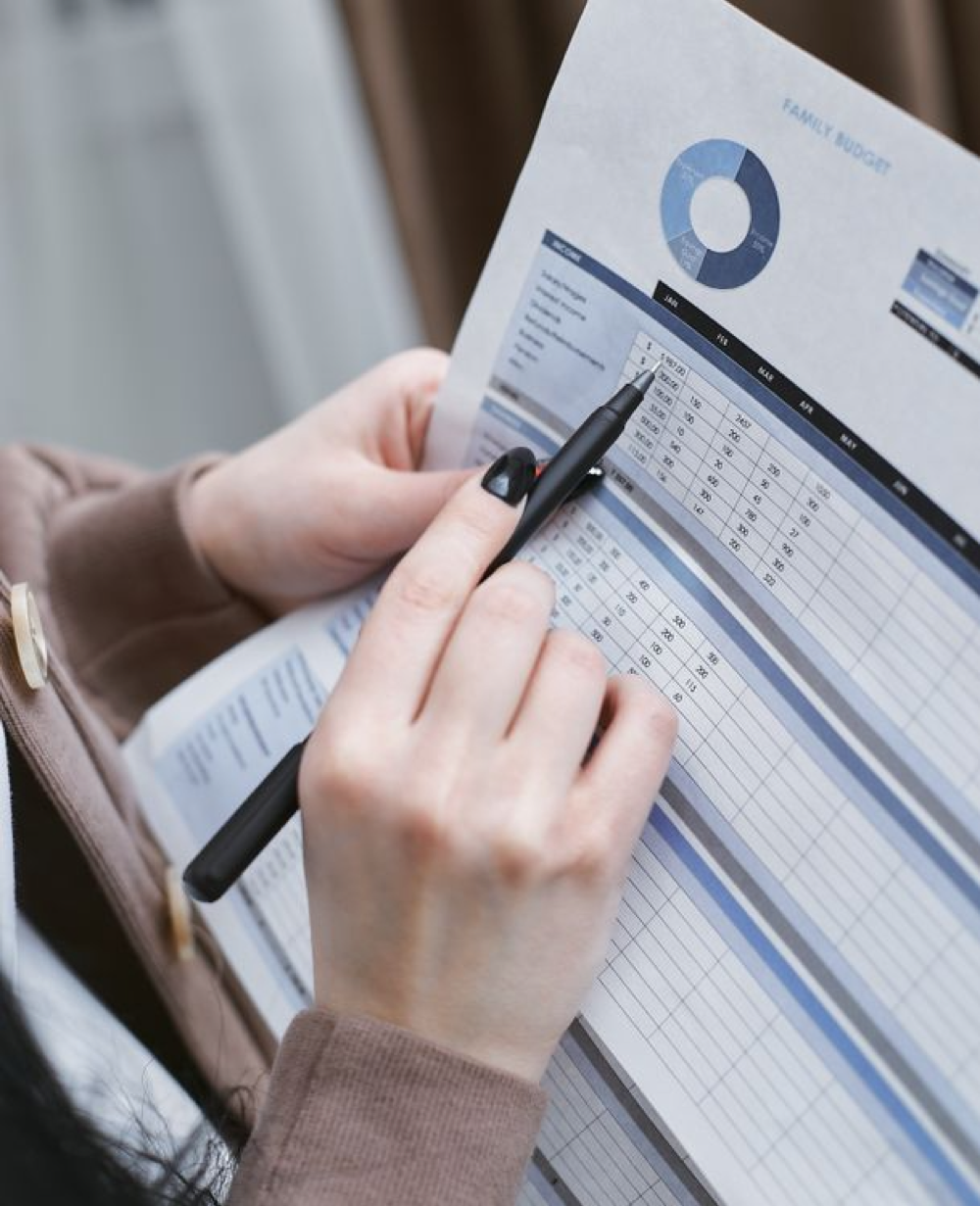 A person holding a black pen writing on white paper