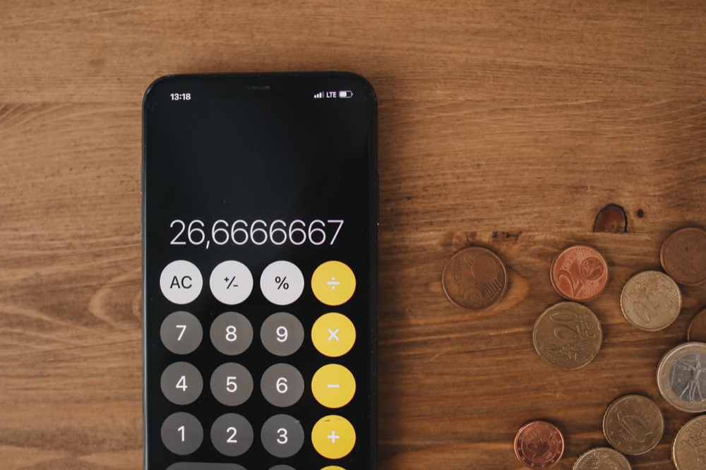 Close up view of loose change and calculator on wooden surface