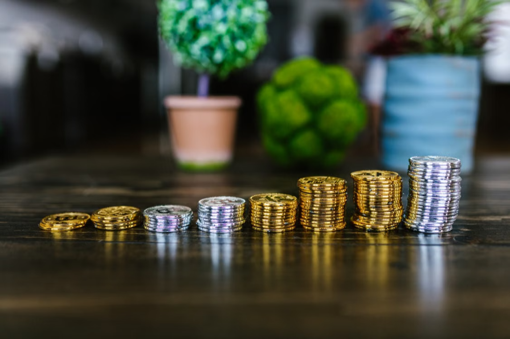Gold and silver coin stacks progressively growing larger on a table