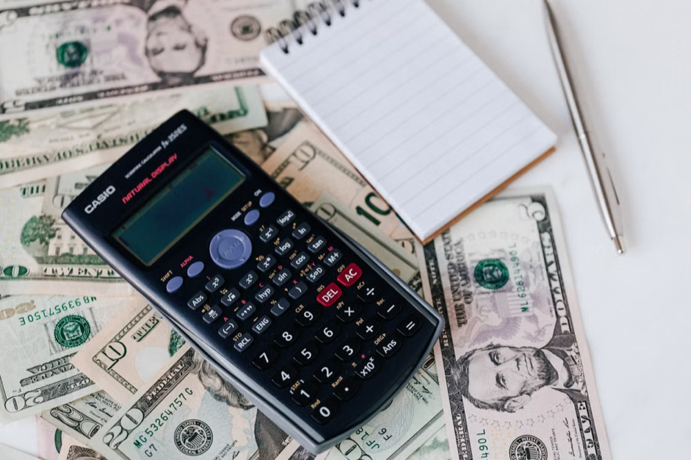Calculator and note pads placed on top of bank notes