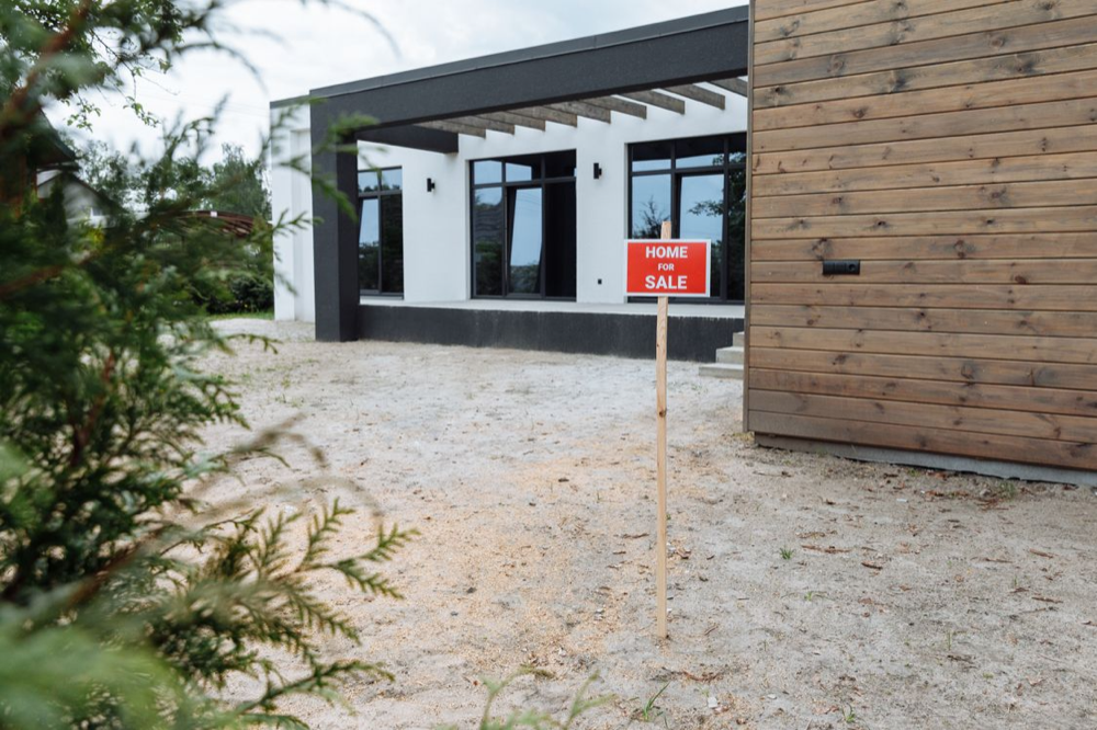 Home for sale red sign in front of a modern house