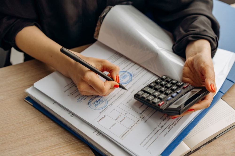 A person examining a document with a pocket calculator
